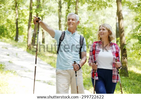 Portrait of senior couple enjoying a nordic walk. Active elderly woman and man walking on the forest and smiling.