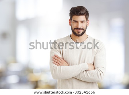 Portrait of confident sales man standing at office with arms crossed and smiling while looking at camera.