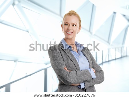 Portrait of attractive middle age businesswoman standing at office with arms crossed. Business people.