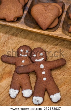 two gingerbread man and gingerbread hearts on a wooden background