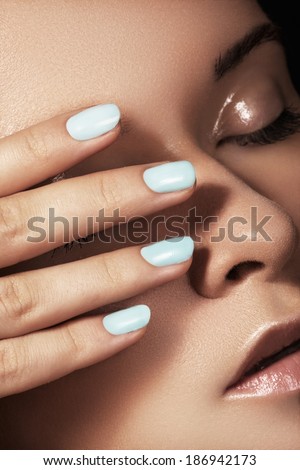 Make-up & cosmetics, manicure. Close-up portrait of beautiful woman model face with clean skin on white background. Natural skincare beauty, clean soft skin, manicure. Suntan girl with sky blue nails