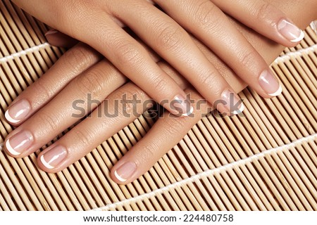 Beautiful woman\'s nails with perfect french manicure on natural bamboo. Care for female hands