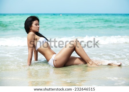 Beautiful young woman model in white bikini swim wear on a beach. Magic ocean and nature. Spa relax, vacation and resort. Travel to exotic countries