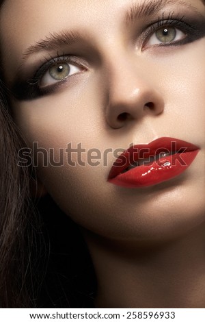 Close-up portrait of sexy caucasian young woman model with glamour red lips make-up, eye arrow makeup, purity complexion. Perfect clean skin. Retro beauty style.