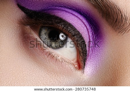 Cosmetics & make-up. Beautiful female eye with sexy black liner and bright purple makeup. Fashion classic arrow shape on woman's eyelid. Chic evening make-up