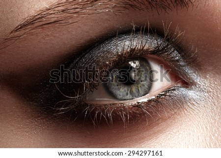 Elegance close-up of female eye with dark gray eyeshadow. Macro shot of beautiful woman\'s face part. Wellness, cosmetics and make-up.