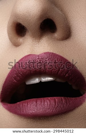 Close-up of woman\'s lips with bright fashion dark red makeup. Macro cherry lips make-up. Evening sexy visage