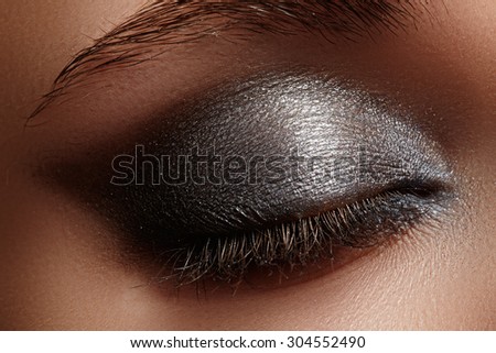 Elegance close-up of female eye with dark gray eyeshadow. Macro shot of beautiful woman's face part. Wellness, cosmetics and make-up.