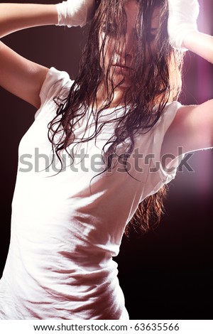 Healthy lifestyle and extreme sports, dance. Beautiful woman model stretching in white t-shirt on dark background. Street dancer.