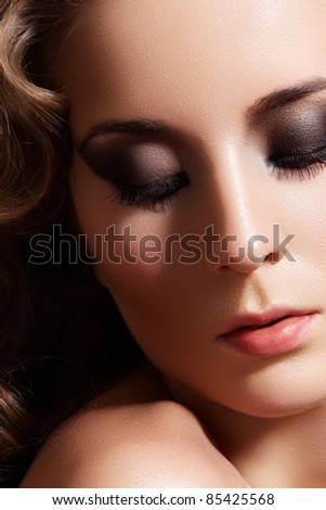 Close-up of beautiful woman model with perfect curvy hair style, retro evening smoky eye make-up and pale lips