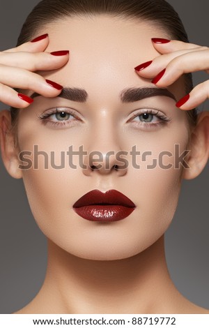 Luxury fashion style, manicure, cosmetics and make-up. Dark lips makeup & nails polish. Close-up portrait of female model with red lipstick, fingernails and clean skin