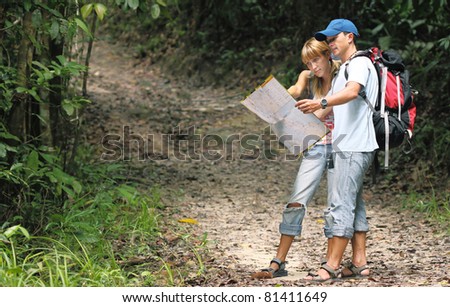 Couple of young people looking at the map in the forest