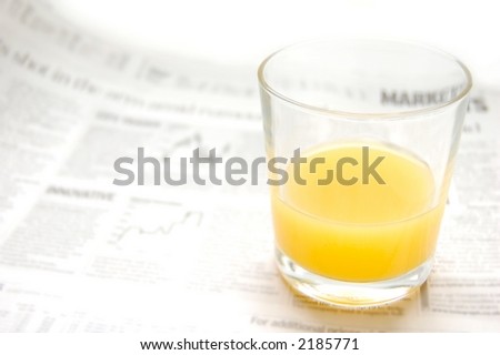 Glass of refreshing orange fruit juice over out of focus business paper with graphs, macro