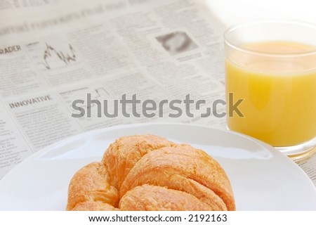 Glass of refreshing orange fruit juice and croissant over business paper with graphs and word \'innovative\', macro