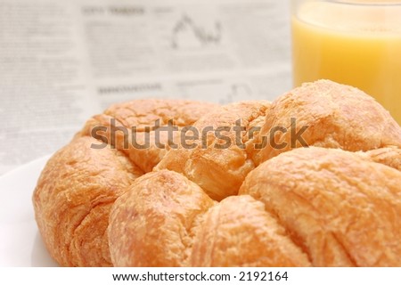 Glass of refreshing orange fruit juice and croissant over business paper with graphs out of focus, macro