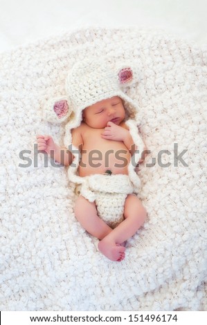 Eight day old sleeping newborn baby wearing a crocheted lamb hat and diaper cover.