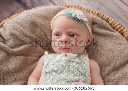 An alert seven week old baby girl lying in a wicker basket.