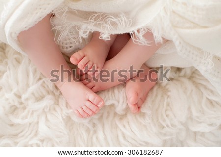 A closeup shot of the feet of twin girl babies. Shot in the studio on a sheepskin rug.