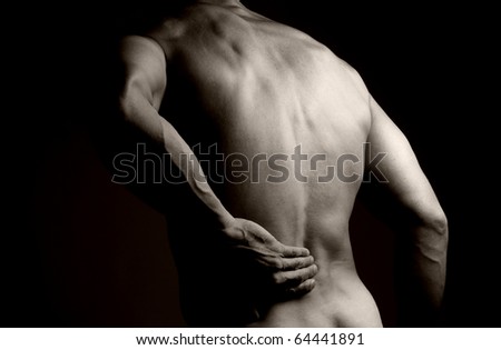 Black and white image of the back of a muscular man. He is rubbing his lower back as if to indicate a backache.