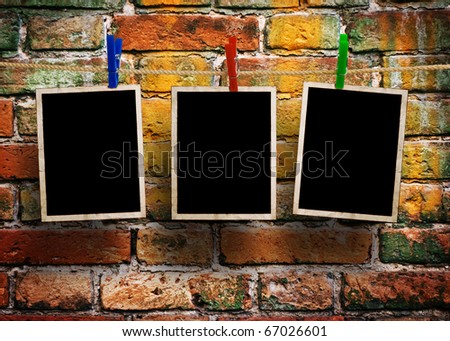 pictures on a rope with clothespins, with clipping path for images, in front of a brick wall