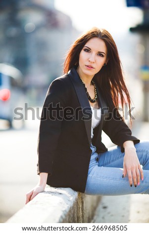beautiful girl on the background of the road sat down on the curb