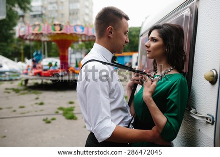 man and woman is hidden from view behind a trailer in the park with attractions