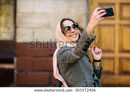 beautiful girl in a coat on the street makes selfie