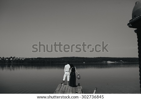 Young couple standing on a deck by the water, looking into the distance