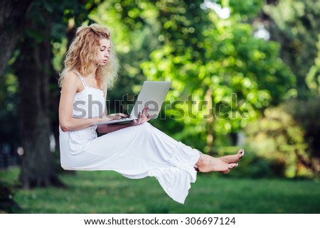 beautiful girl levitates in nature with laptop
