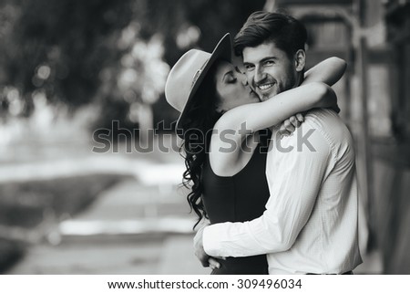 beautiful girl embraces and kisses her boyfriend in the park
