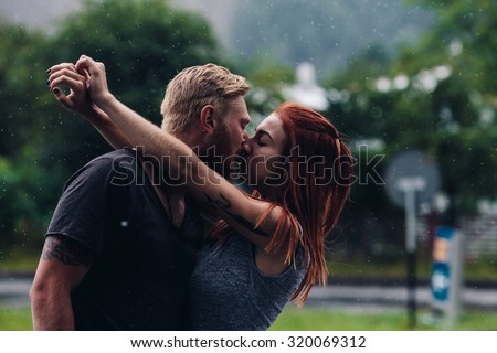 beautiful couple kissing outside in the rain