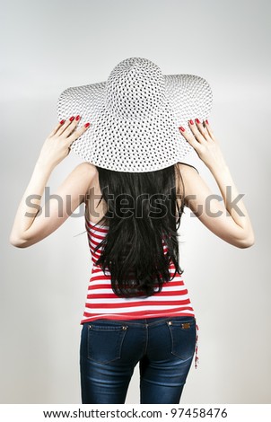 Girl is back with a hat on a gray background
