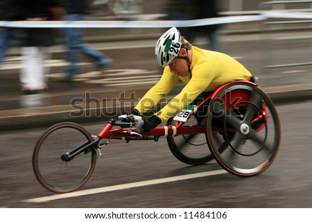 a fast moving wheelchair athlete competes in a marathon, with motion blur