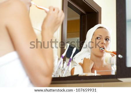 Woman in white towels bathroom brushing teeth