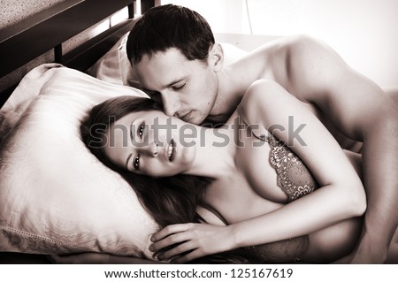 Young man kissing woman in darkness bedroom on bed