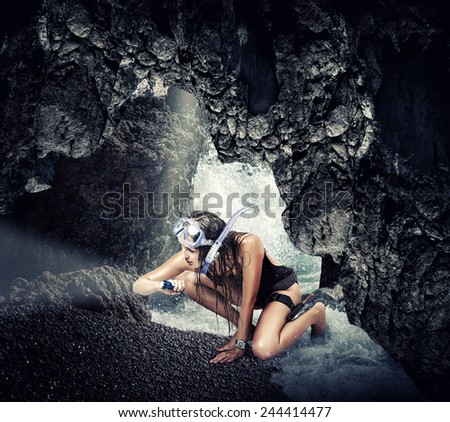 Adventure. Woman traveler and explorer in sea cave, shining a flashlight into the darkness searching treasures