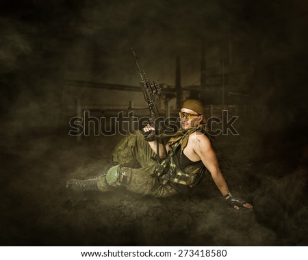 Military man soldier Holding automatic machine gun and sitting on a ground