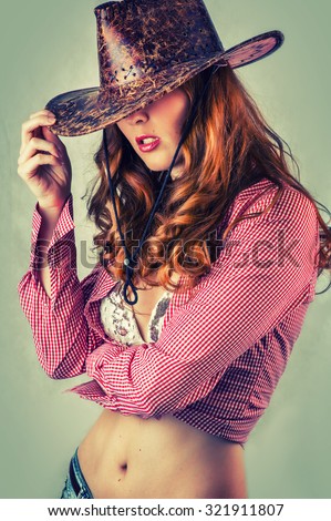 Beautiful cowgirl style woman wearing cowboy hat, studio shot