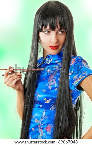 A european model in traditional dark blue japan dress holding chopsticks on green background
