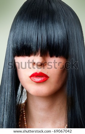 Closeup portrait of beautiful fashion woman with seductive red lips and creative black hairstyle with bang covering her eyes