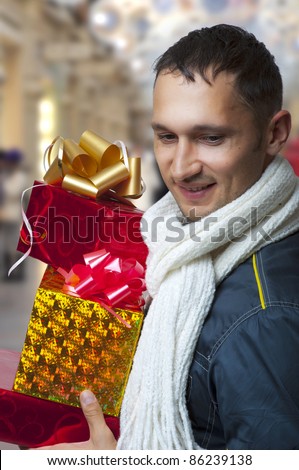 Young adult handsome man with christmas gifts or presents busy shopping at the shopping mall and smile