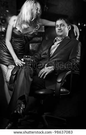 Young loving couple - sexy woman and rich man with glass of whiskey. Black and white