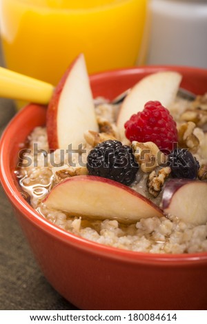 Bowl of delicious steel cut oats with fresh fruit, honey and orange juice