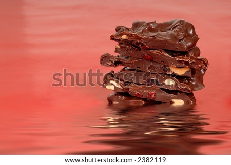 Chocolate cashew and dried cherry bark in water on a red background horizontal view