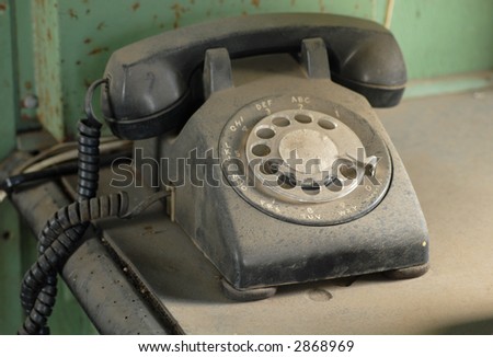 Old dusty rotary dial telephone resting on a table