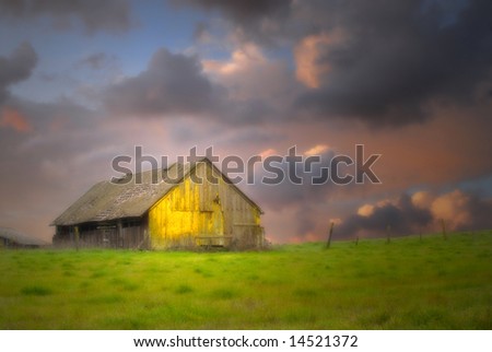 Old rustic barn in a field under dark skies with soft focus and dramatic lighting