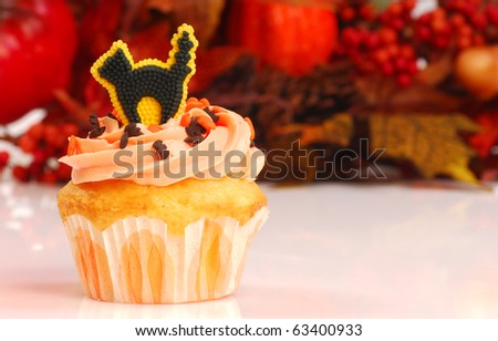 Delicious Halloween cupcake with butter cream frosting and fall foliage in the background