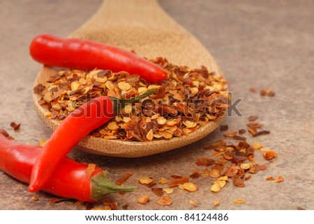 Hot red chili peppers and red pepper flakes on a wooden spoon