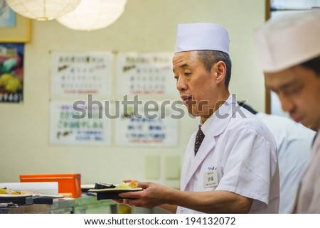 TOKYO, JAPAN - NOVEMBER 25: Japanese Sushi Chef  in Tokyo, Japan on November 25, 2013. Unidentified Japanese Sushi Chef prepares a dish of sushi for his customer in a restaurant