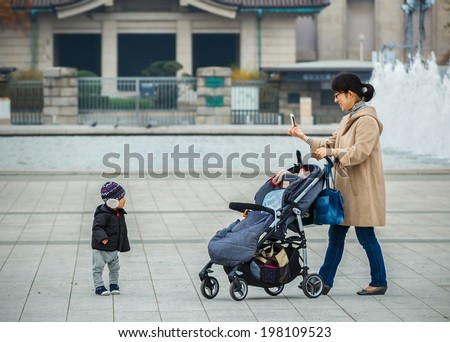 TOKYO, JAPAN - NOVEMBER 25: Ueno Park in Tokyo, Japan on November 25, 2013. Unidentified Japanese mother use a smartphone takes picture of her child